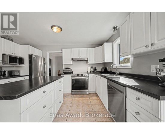 A kitchen with white cabinets and black countertops.