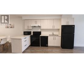A kitchen with black appliances and white cabinets.