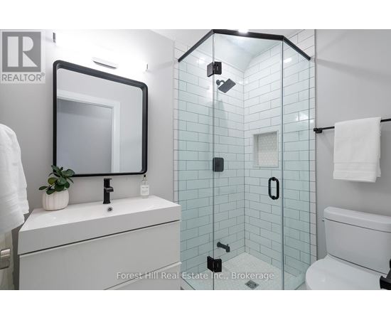 A white bathroom with a glass shower stall and a white toilet.