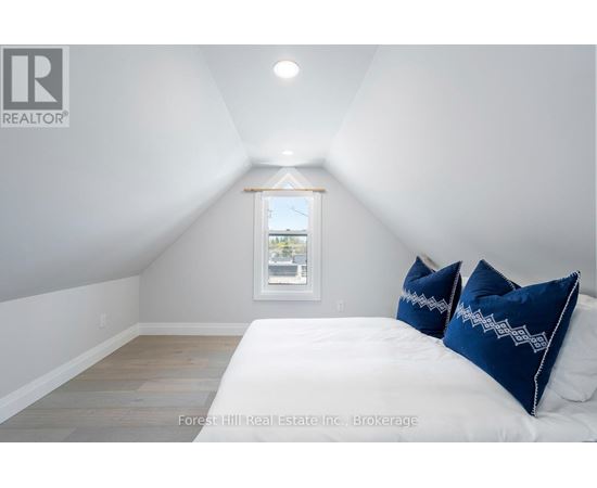 A bedroom with a bed, two pillows, and a window.