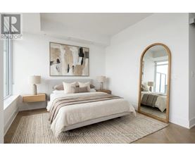 A bedroom with a large bed, a painting on the wall, and a mirror on the wall.
