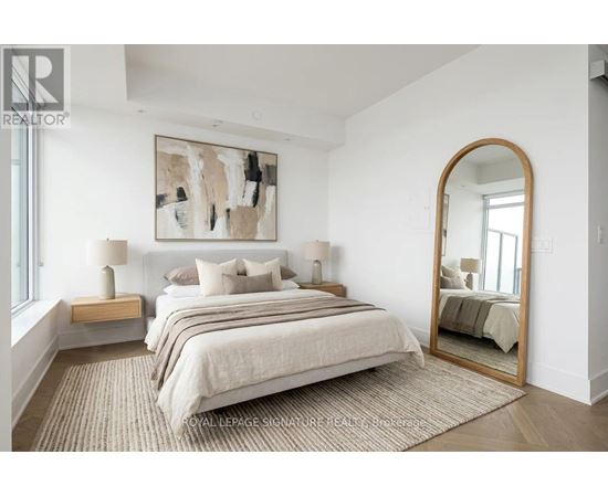 A bedroom with a large bed, a painting on the wall, and a mirror on the wall.
