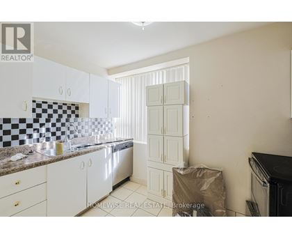 A kitchen with white cabinets and a checkered backsplash.