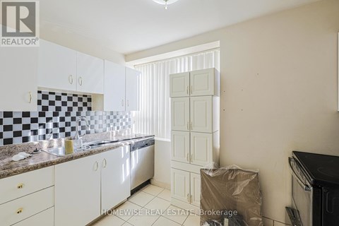 A kitchen with white cabinets and a checkered backsplash.