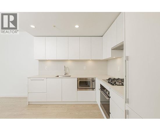 A white kitchen with a sink, oven, and stove.