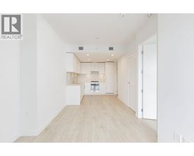 A spacious, empty room with a kitchen area in the background.