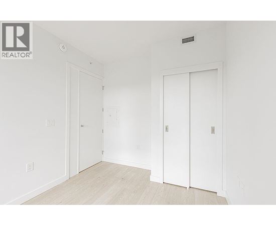 A white room with a door on the left and a white door on the right.