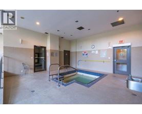 A swimming pool in a room with a chair and a door.