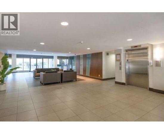 A spacious lobby area with a reception desk and a potted plant.