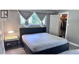 A bedroom with a large bed and a small table with a lamp.