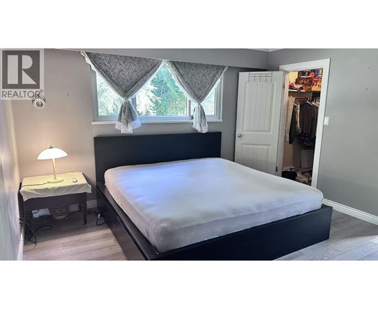 A bedroom with a large bed and a small table with a lamp.