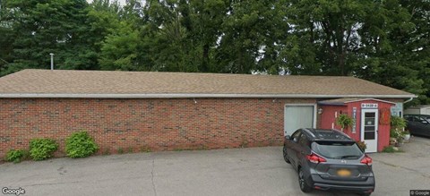 A black car is parked in front of a red building.