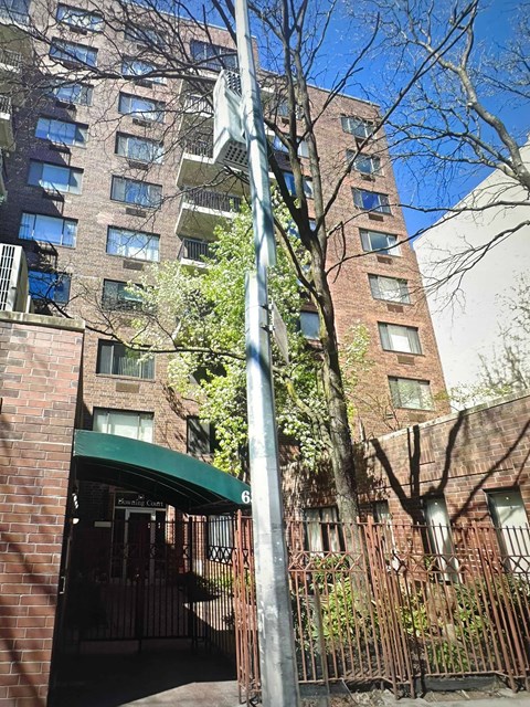 A tall building with a green awning and a gate in front.