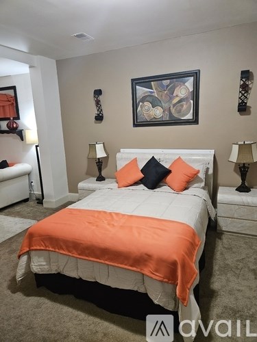 A bedroom with a bed covered in an orange blanket.