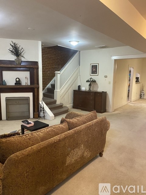 A living room with a brown couch and a fireplace.