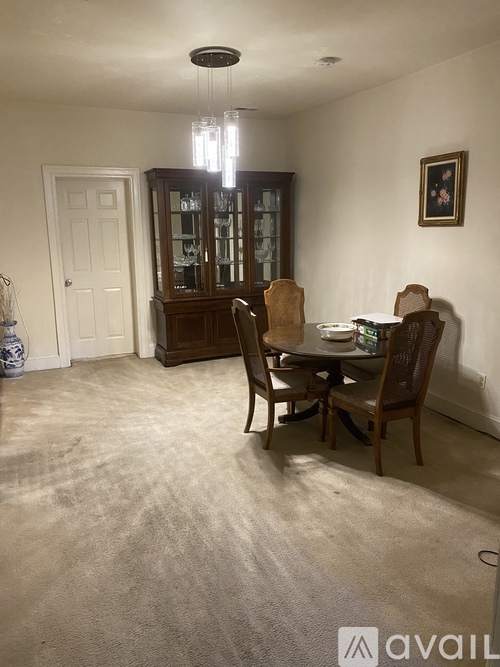 A dining room with a table set for two and a china cabinet.