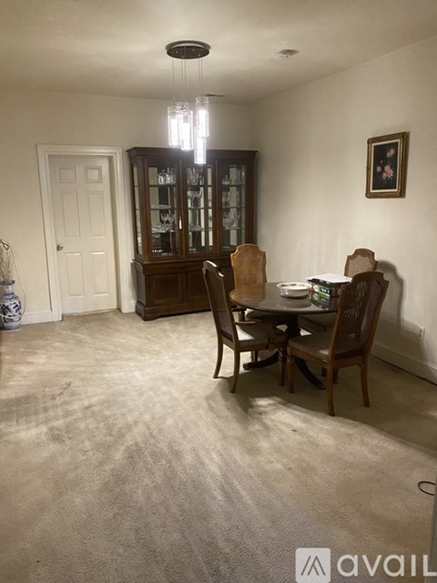 A dining room with a table set for two and a china cabinet.