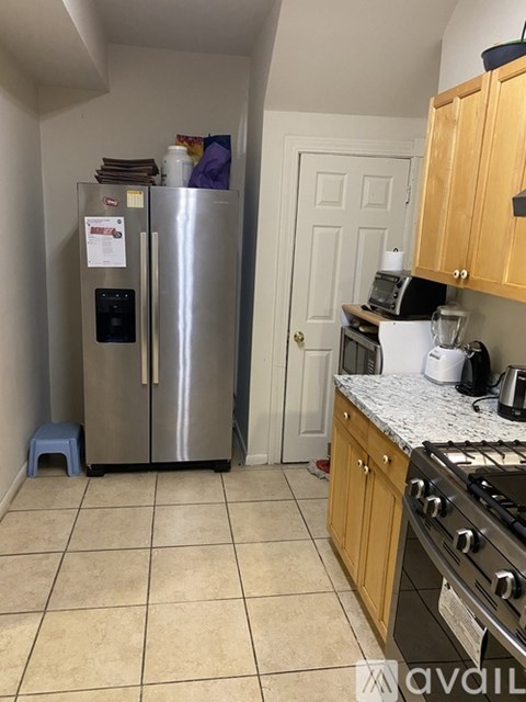 A kitchen with a stainless steel refrigerator and wooden cabinets.