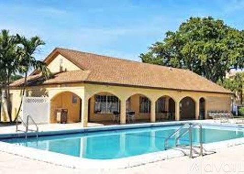 A pool and a building with a brown roof and windows.