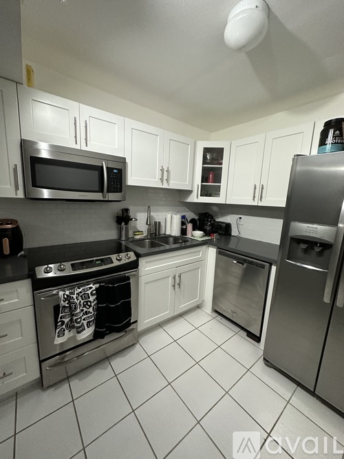 A kitchen with white cabinets and a black counter top.