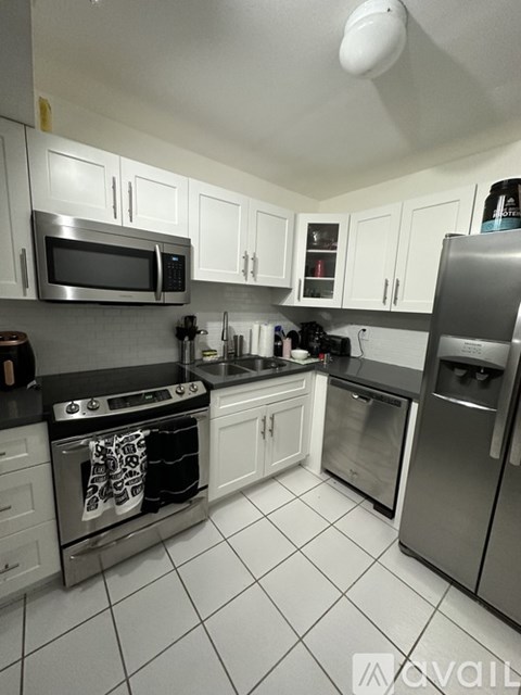A kitchen with white cabinets and a black counter top.