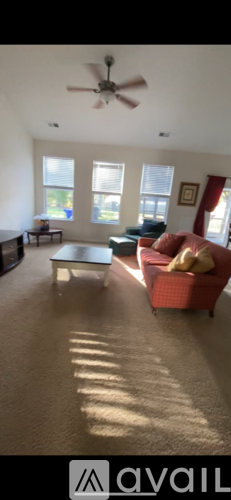 A living room with a ceiling fan and a red couch.