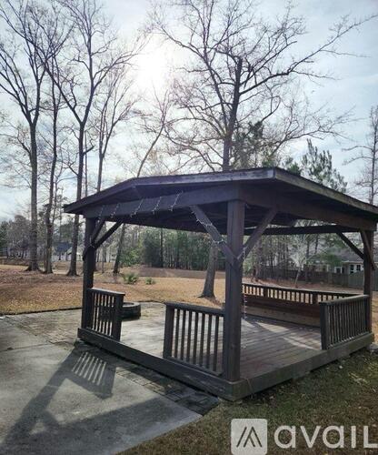 A wooden gazebo with a roof and a set of stairs leading up to it.