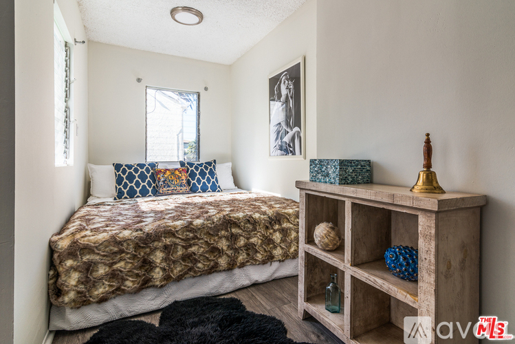 A bedroom with a bed, a wooden shelf, and a window.