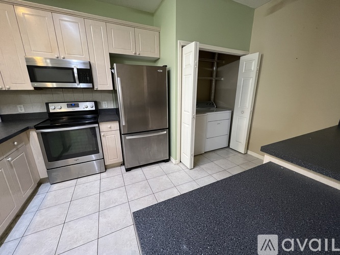 A kitchen with a black counter top and stainless steel appliances.