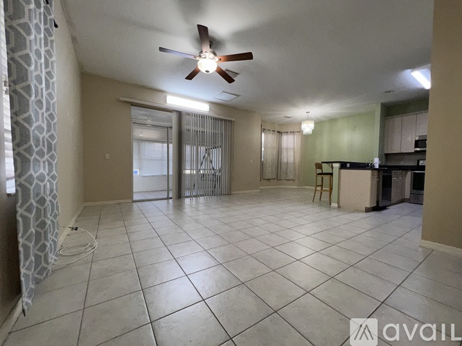 A spacious room with a ceiling fan and tiled flooring.