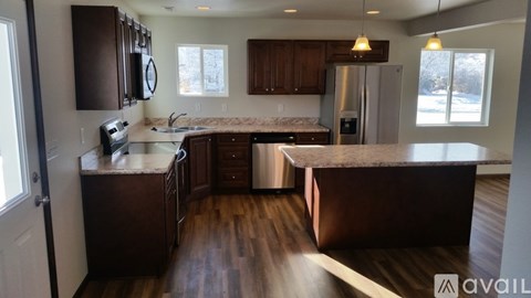 A kitchen with dark wood cabinets and a marble countertop.