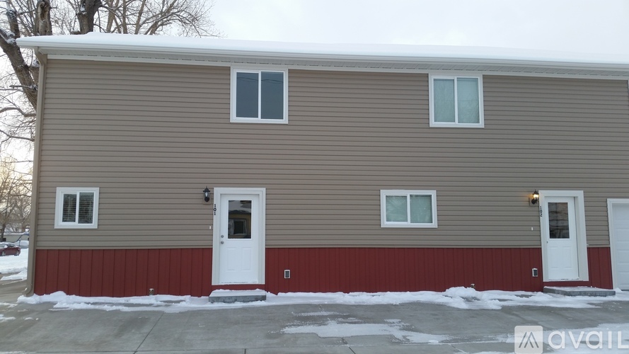 A two-story house with a red siding on the bottom floor and beige siding on the top floor.