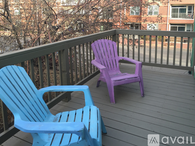 Two chairs on a balcony with a view of apartment buildings.