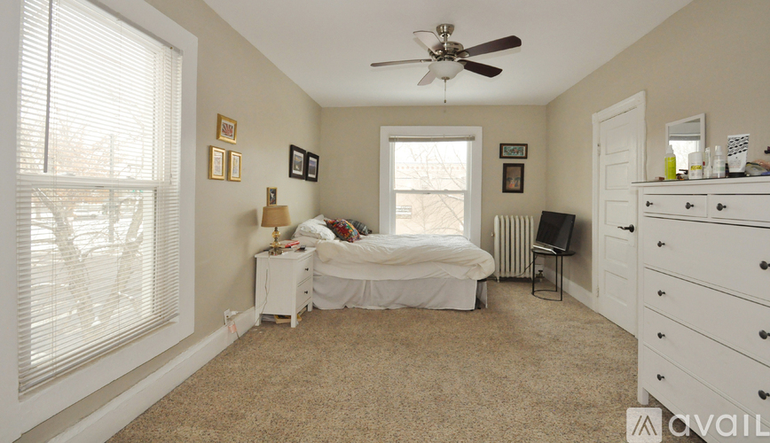 A bedroom with a bed, dresser, and window with blinds.