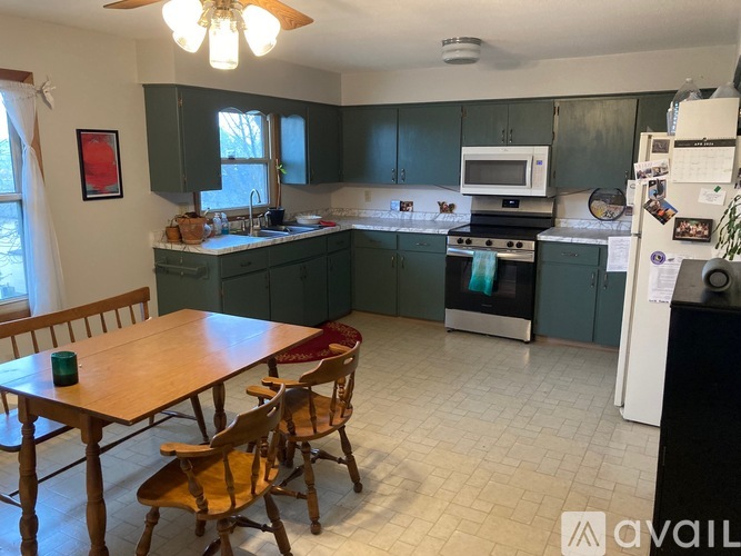 A kitchen with green cabinets and a wooden table.