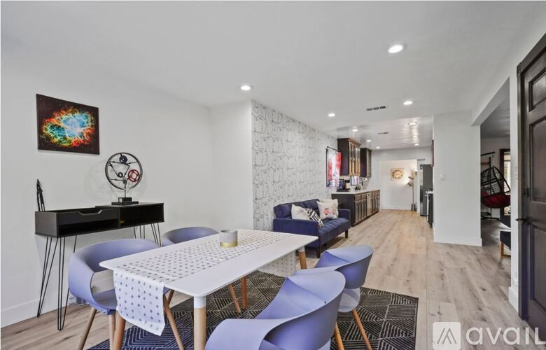 A modern dining room with a white table and blue chairs.
