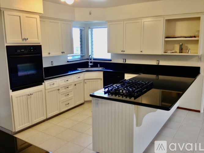 A kitchen with white cabinets and black countertops.
