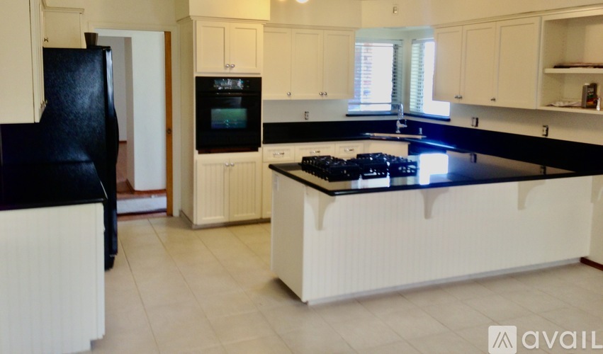 A kitchen with black appliances and white cabinets.