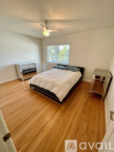 A bedroom with a bed, a ceiling fan, and a window.
