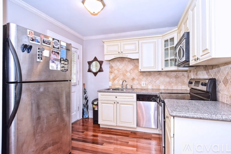 A kitchen with a stainless steel refrigerator and wooden floors.