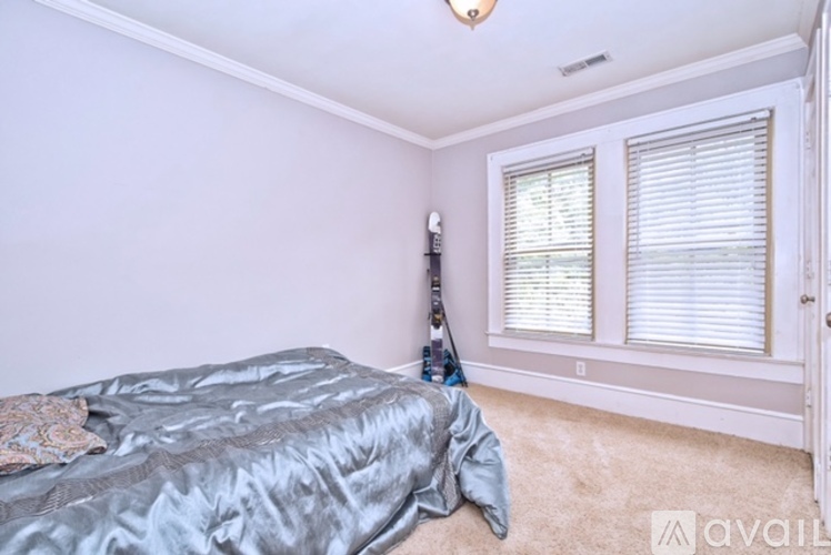 A bedroom with a bed and a window with blinds.