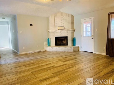 A living room with a fireplace and wooden floors.