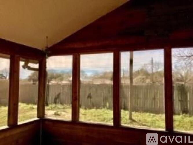 A room with a view of a fence and trees.