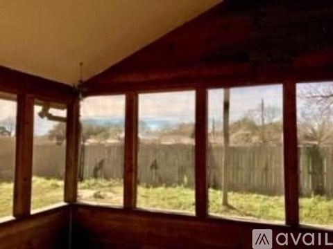 A room with a view of a fence and trees.