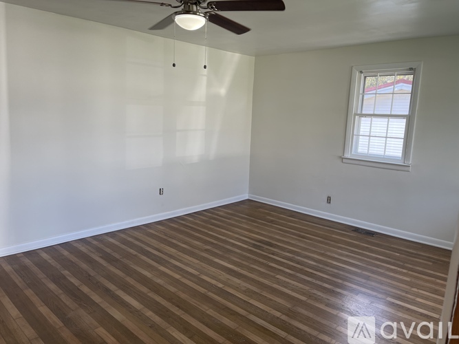 A room with a ceiling fan and wooden flooring.