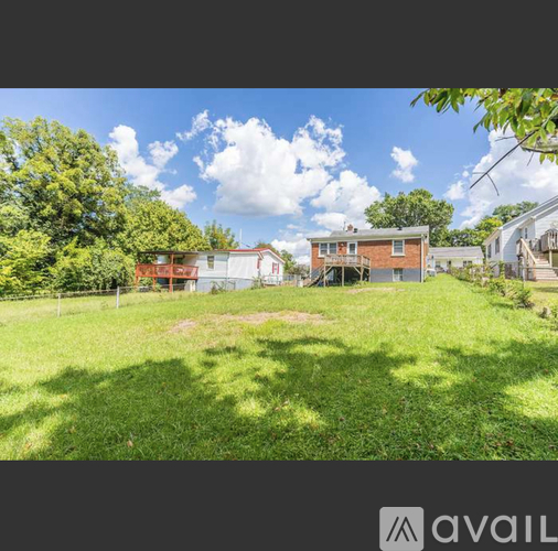 A grassy area with a house and trees in the background.
