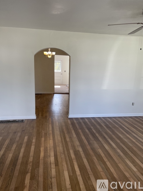 A room with wooden flooring and a chandelier.