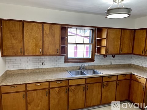 A kitchen with wooden cabinets and a window above the sink.