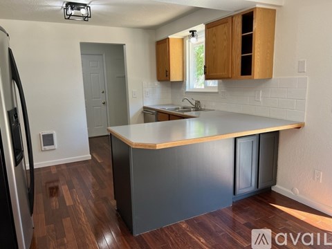 A kitchen with a refrigerator on the left and a countertop with a sink.