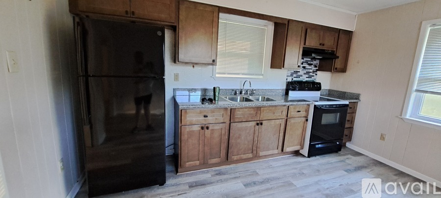 A kitchen with a black fridge and wooden cabinets.